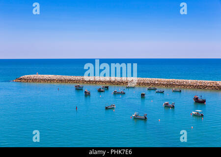 Many small boats lying near jetty in sea Stock Photo