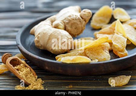 Ginger root and candied ginger on a wooden plate. Stock Photo