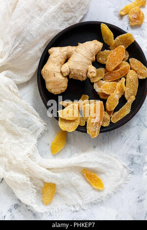 Ginger root and candied ginger on a wooden plate. Stock Photo