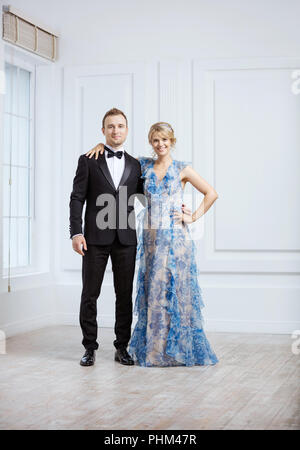 Cheerful young couple looking at camera and smiling. Couple in luxury fashionable clothes posing indoors. Stock Photo