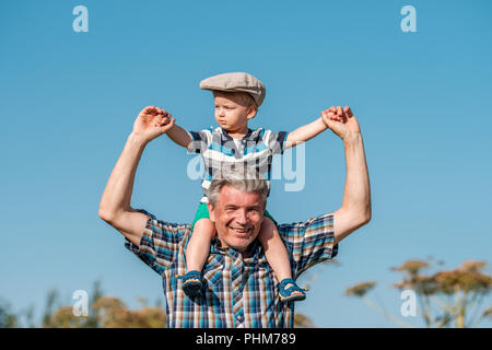 Grandfather carries grandson toddler boy on his shoulders Stock Photo