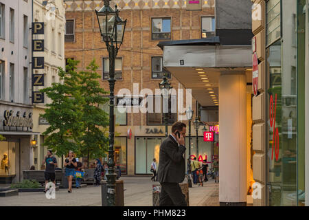 A man talking on a mobile phone on a shopping street in Dusseldorf, Germany. Stock Photo
