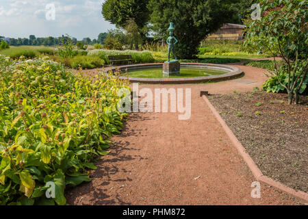 View of the statue, trees  and flowers along a pathway at Rheinpark Golzheim park in Dusseldorf, Germany on a sunny day. Stock Photo