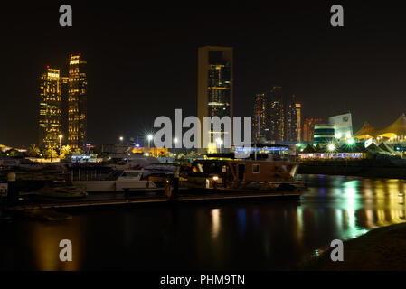 Abu Dhabi, UAE - July 23, 2018: A view showing parts of the city skyline in background and boats in foreground across the Abu Dhabi Marina at night Stock Photo