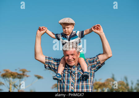 Grandfather carries grandson toddler boy on his shoulders Stock Photo