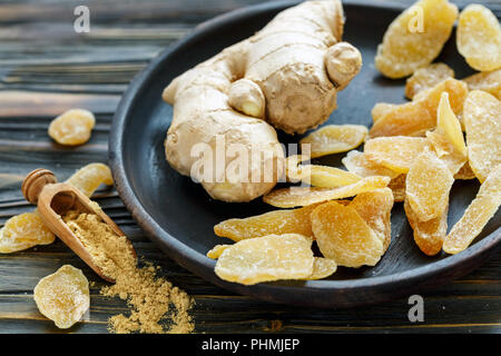 Ginger root and candied ginger on a wooden plate. Stock Photo