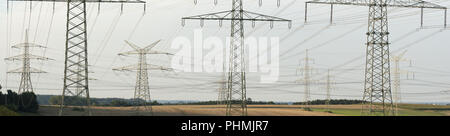 Many high-voltage pylons for transporting electricity from a power plant Stock Photo