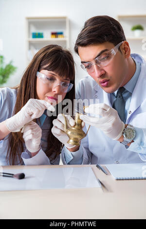 Two archeologists looking at ancient gold lamp Stock Photo