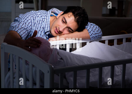 Young father dad sleeping while looking after newborn baby Stock Photo