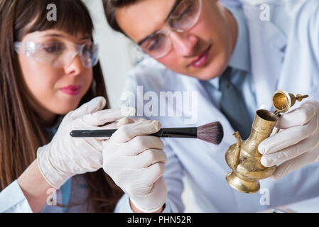 Two archeologists looking at ancient gold lamp Stock Photo