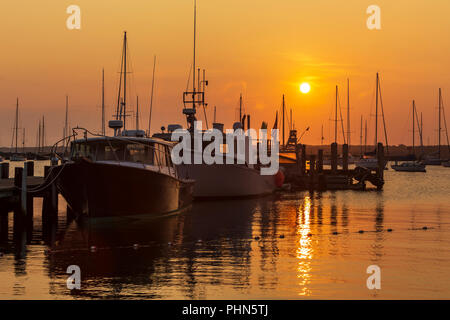 The sun rises over fishing boats and pleasure craft in Vineyard Haven Harbor in Tisbury, Massachusetts on Martha's Vineyard. Stock Photo