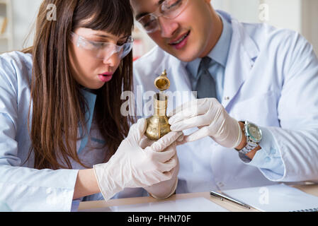 Two archeologists looking at ancient gold lamp Stock Photo