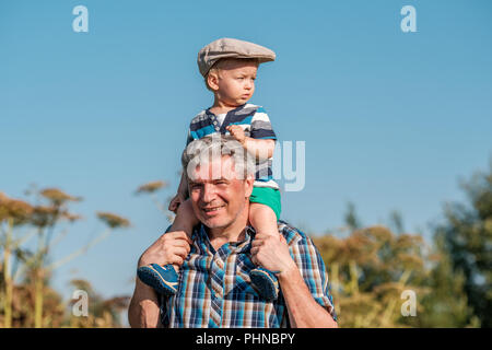 Grandfather carries grandson toddler boy on his shoulders Stock Photo