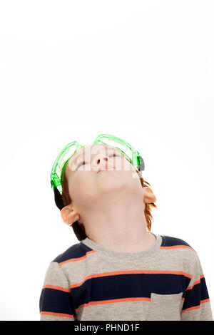 beautiful red-haired boy in protective construction glasses, looking up at light background Stock Photo