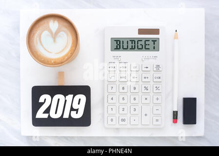 Top view of new year 2019 budget on calculator and coffee cup on white marble block and stack on grey marble table.financial planning Stock Photo