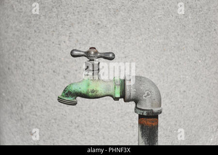 profile of a bronze metallic faucet outdoors with a blank wall background Stock Photo