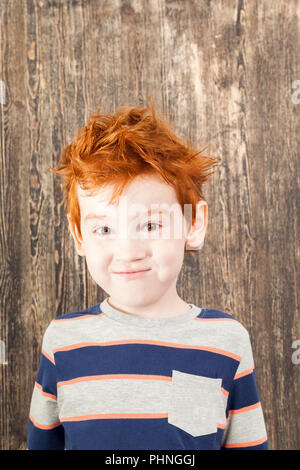 red-haired boy with disheveled hair, close-up on a black wooden background Stock Photo