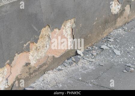 A damaged house wall and flaked exterior plaster with a large hole Stock Photo