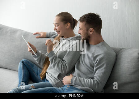 Smiling young couple watching funny video on tablet Stock Photo