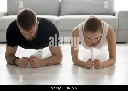Toned young couple stand in forearm plank training together Stock Photo