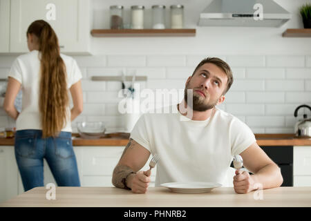Lazy husband bored in kitchen while waiting for breakfast Stock Photo