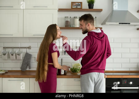 Loving boyfriend feeding girlfriend while cooking food together Stock Photo