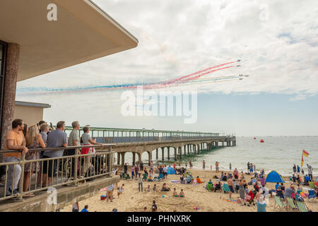 Bournemouth, Dorset, UK, Saturday 1st September 2018. Crowds of people watch from the beach and the pier as the Red Arrows fly past Boscombe Pier at the Bournemouth Air Festival. Stock Photo