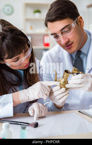 Two archeologists looking at ancient gold lamp Stock Photo