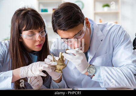 Two archeologists looking at ancient gold lamp Stock Photo