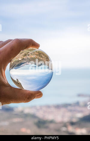 Glass round ball on the beach reflects the sea in summer at sunset ...
