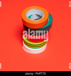 some rolls of colored insulating tape on a red surface Stock Photo