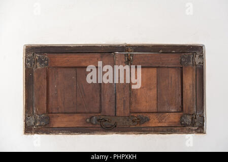 An old wooden shutter in a white wall, Mexico. Stock Photo