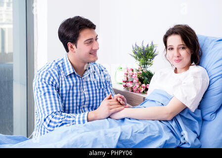 Caring loving husband visiting pregnant wife in hospital Stock Photo