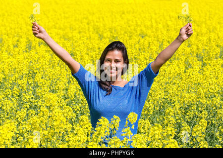 Happy woman arms up in rapeseed field Stock Photo