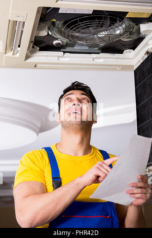 Repairman repairing ceiling air conditioning unit Stock Photo