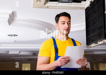 Repairman repairing ceiling air conditioning unit Stock Photo