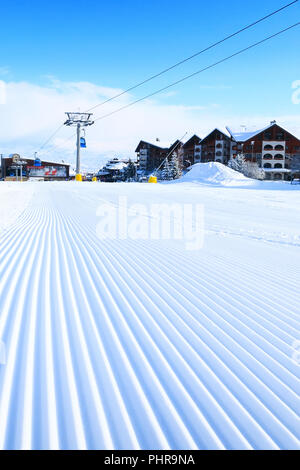 Close-up groomed snow at Bansko resort, Bulgaria panorama with ski slope and cable car lift Stock Photo