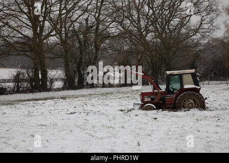 Tractor stuck in snowy field winter Stock Photo