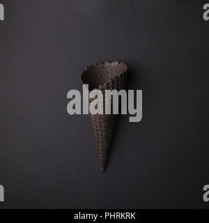 Empty Black Ice Cream Cone on black background, monochrome minimal closeup Stock Photo