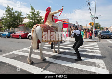 AS per tradition, a Sikh groom on a white horse heads to his wedding following a procession of his family and friends. In Richmond Hill, Queens, NY Stock Photo