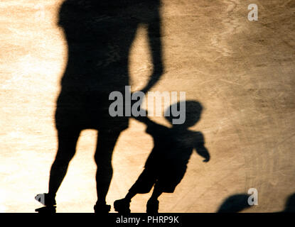 Shadows silhouettes of mother and son walking on misty summer promenade in sepia black and white Stock Photo
