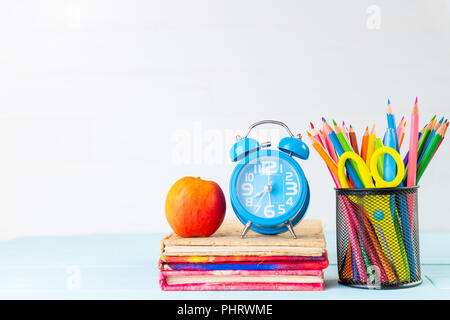 Education or back to school Concept. school office supplies with alarm clock and apple. pencils in mini shopping cart put on stack of book on white wo Stock Photo