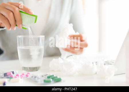 Young business woman sick in the office. pills, tissue and laptop on table. Healthcare And Medical concept. Stock Photo