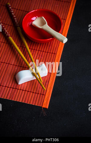 Table setting in red color for asian cuisine dinner with chopsticks Stock Photo