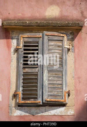 an old greek building with peeling paint on some old wooden window shutters in a shabby chic or rustic farmhouse style. Stock Photo