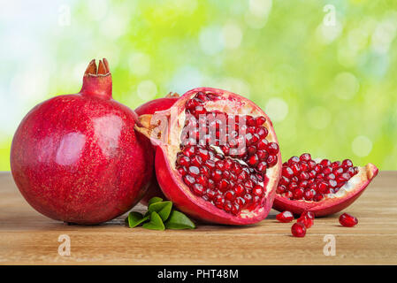 pomegranates whole and cut on wooden table Stock Photo