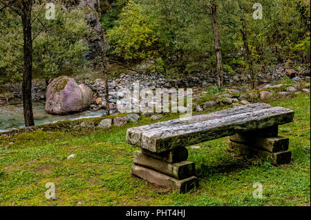 railway sleepers for street furniture in the lawn at the edge of a mountain stream in autumn Stock Photo
