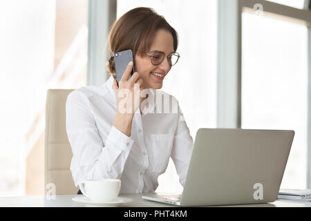 Smiling confident businesswoman making phone call using laptop i Stock Photo