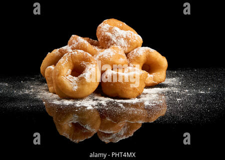 Heap of donuts with sugar powder on black reflective background Stock Photo