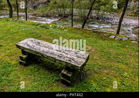 railway sleepers for street furniture in the lawn at the edge of a mountain stream in autumn Stock Photo